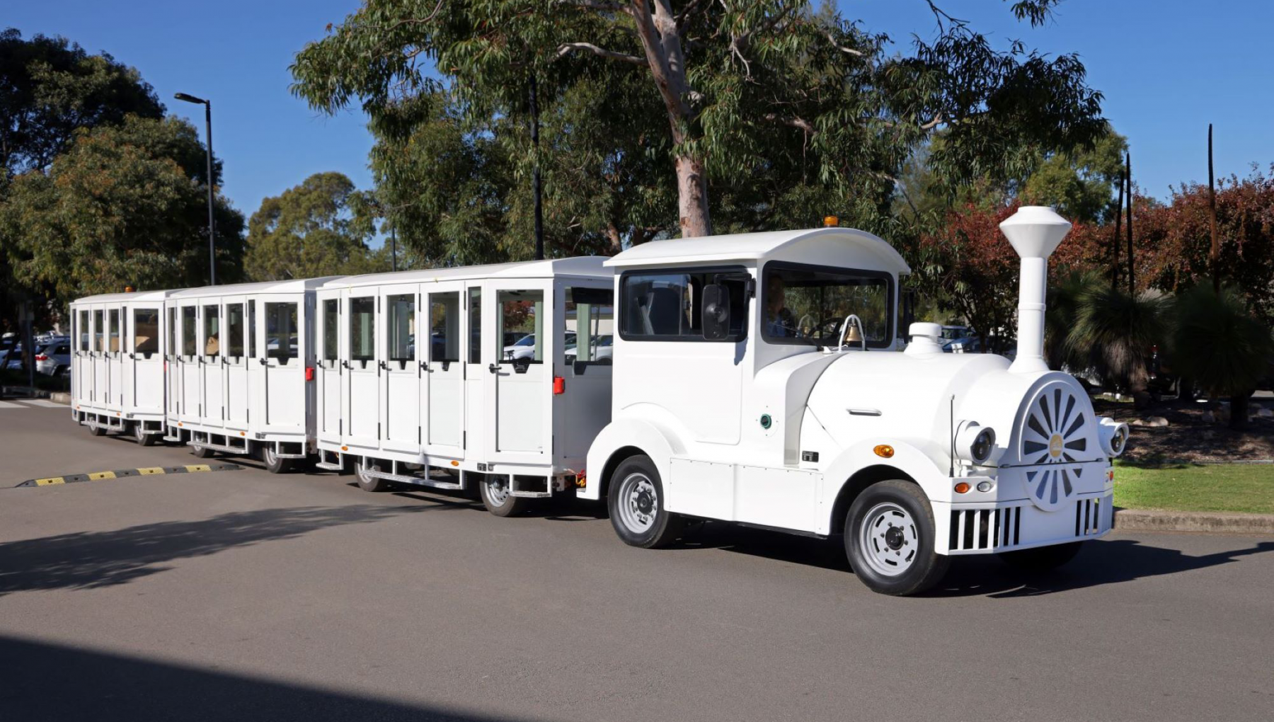 Image of our resort's white electric train set against a backdrop of lush trees.