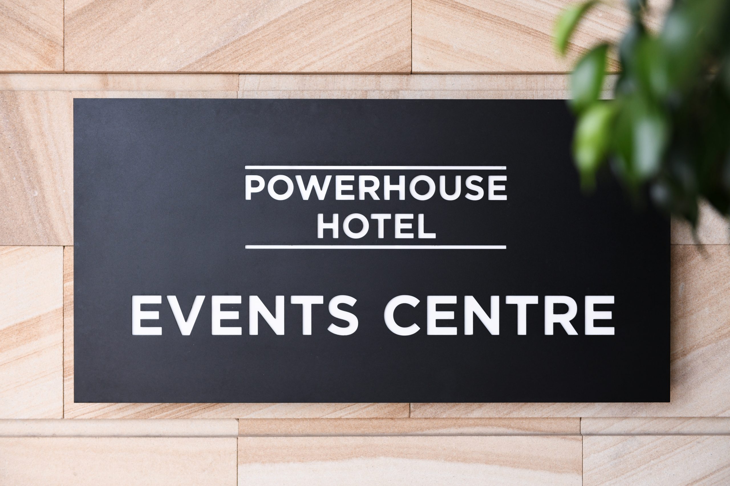 A black signage board displays the text "POWERHOUSE HOTEL" above "EVENTS CENTRE," set against a stone wall.